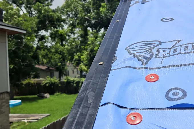 Metal roof edge beside blue underlayment